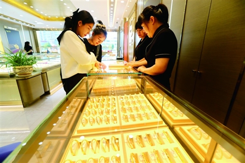 近日,在江苏省连云港市连云区一家金店,顾客在选购黄金饰品。◎新华社发